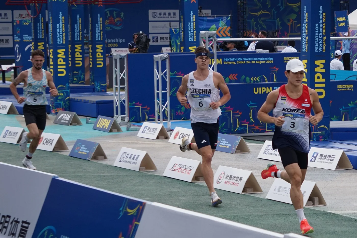 2026 Dünya Modern Pentatlon Şampiyonası laser-run parkurunda koşan üç sporcu.